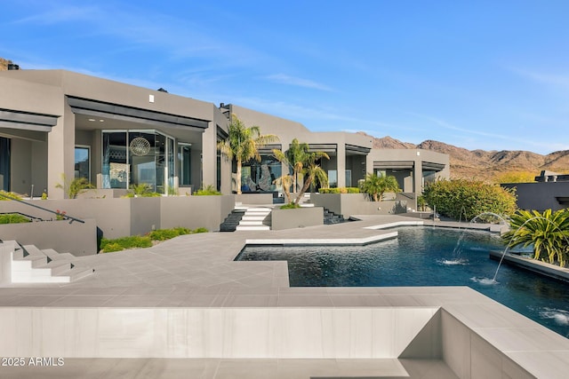 outdoor pool with a mountain view and a patio