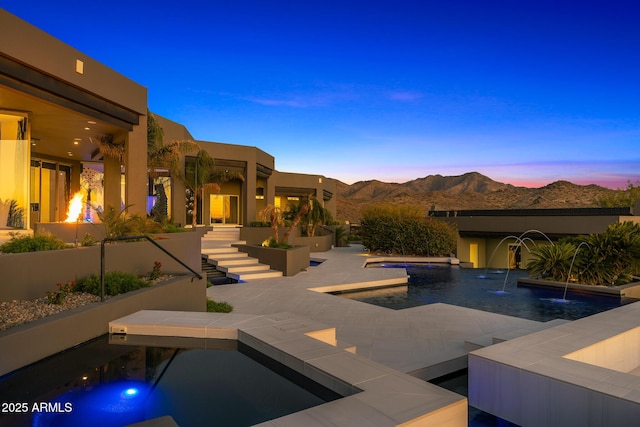 outdoor pool with a patio area, a mountain view, and a jacuzzi