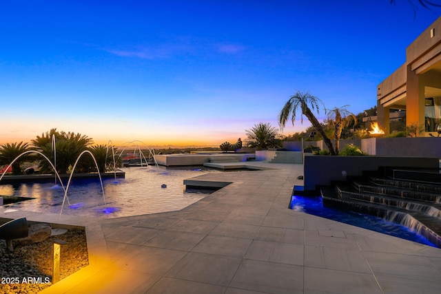 pool at dusk with a patio area