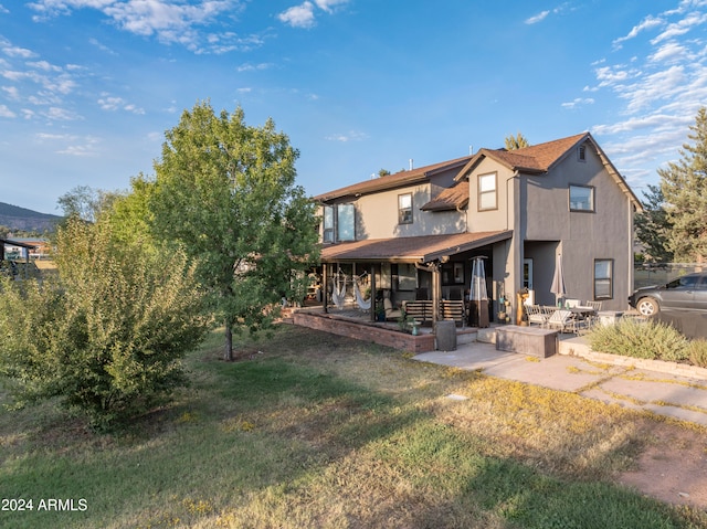 back of property featuring a patio area and a lawn