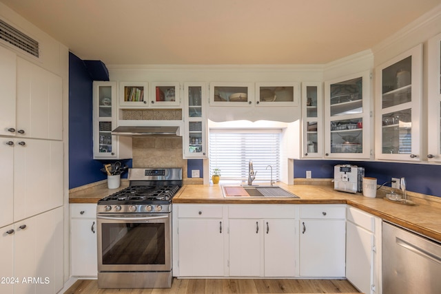 kitchen with sink, white cabinets, gas stove, and range hood