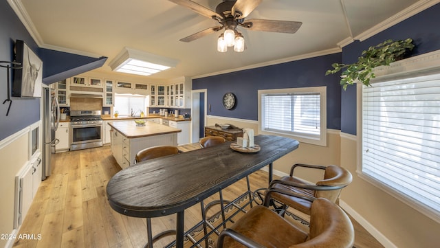 dining space with ornamental molding, sink, light hardwood / wood-style flooring, and ceiling fan