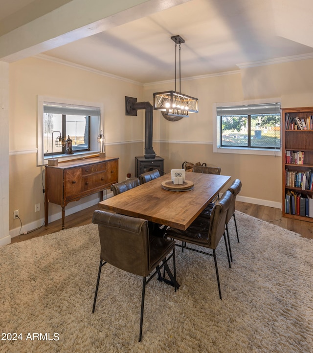 dining room featuring crown molding, a healthy amount of sunlight, a wood stove, and light wood-type flooring