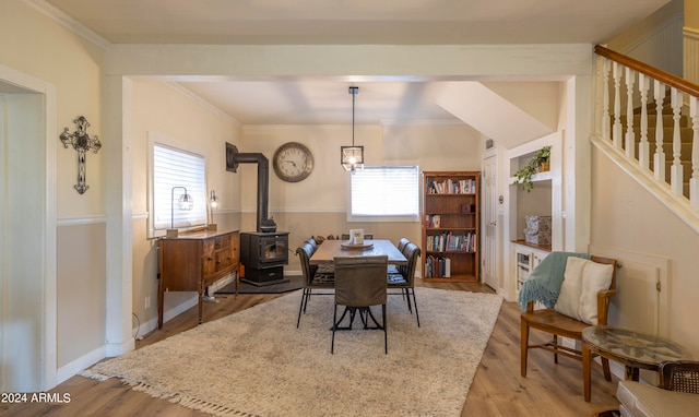 dining room with crown molding, a wood stove, and light hardwood / wood-style flooring