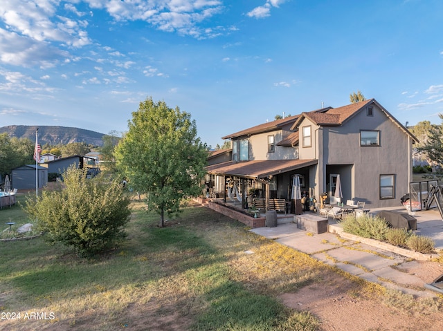 rear view of property with a yard, a mountain view, and a patio