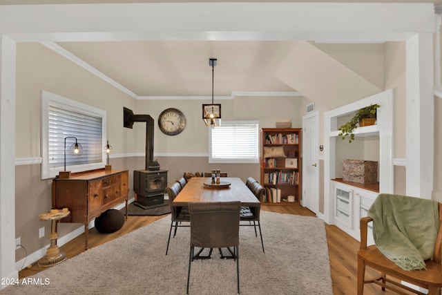 dining area with crown molding, hardwood / wood-style flooring, and a wood stove