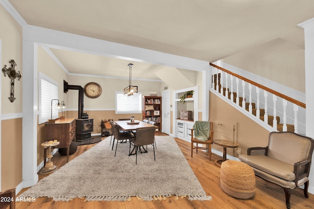 dining area with crown molding, a wood stove, and light hardwood / wood-style flooring