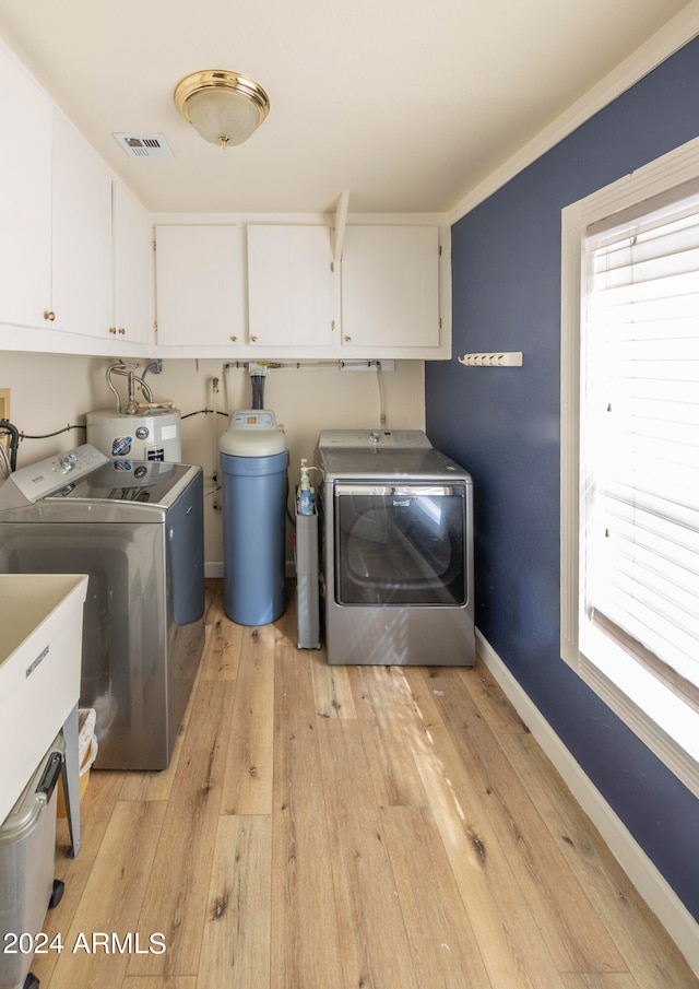 laundry room with washing machine and dryer, light wood-type flooring, water heater, crown molding, and cabinets