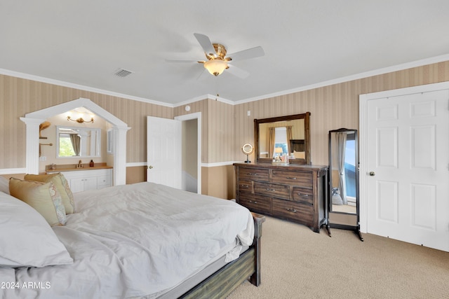 carpeted bedroom with ornamental molding, ensuite bathroom, ornate columns, and ceiling fan