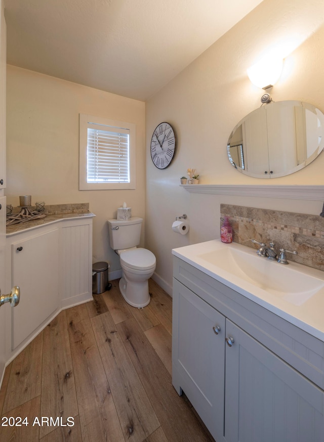 bathroom with toilet, vanity, and wood-type flooring