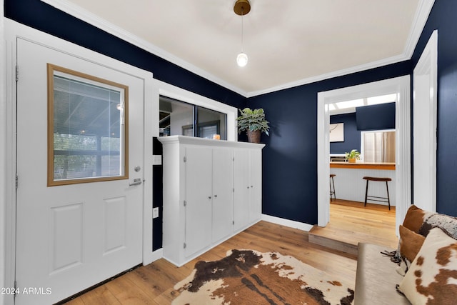 foyer entrance with light hardwood / wood-style floors and crown molding