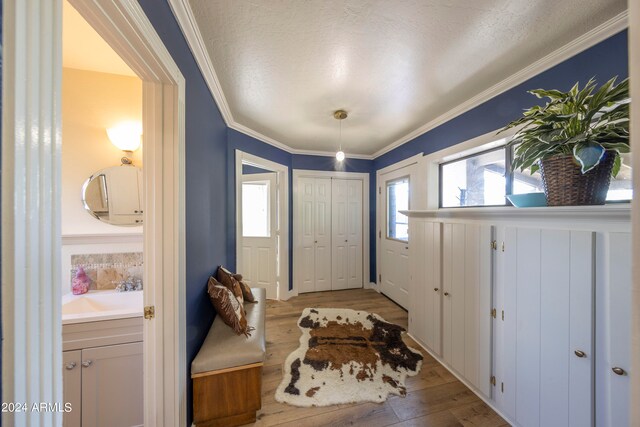 entrance foyer with crown molding, a textured ceiling, and light wood-type flooring