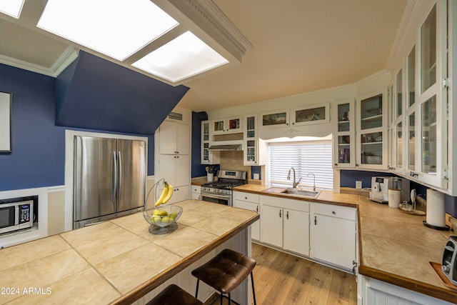 kitchen with appliances with stainless steel finishes, sink, white cabinetry, light hardwood / wood-style floors, and ornamental molding