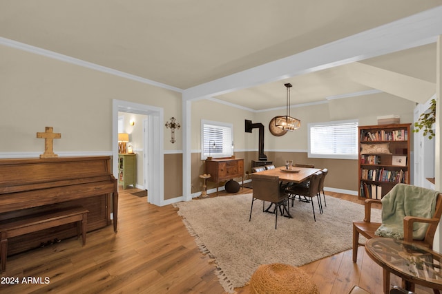 dining room featuring a chandelier, crown molding, light hardwood / wood-style flooring, and a wood stove