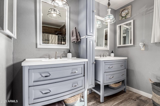 bathroom with a sink, two vanities, wood finished floors, and baseboards