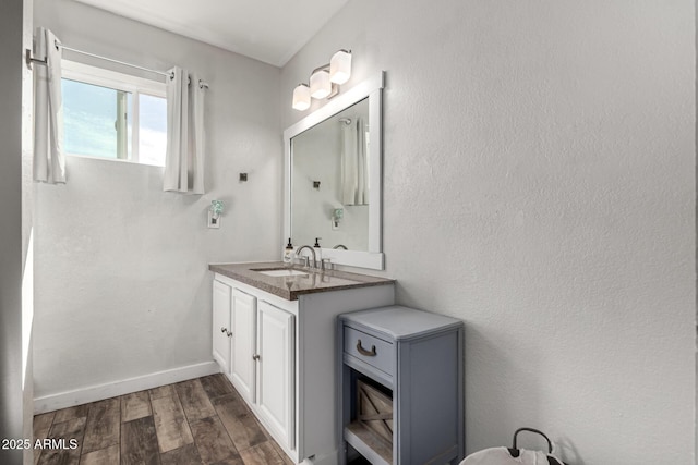 bathroom featuring vanity, baseboards, and wood finished floors