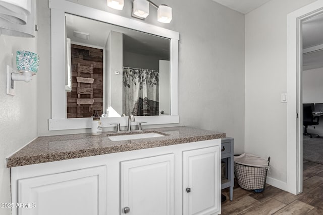 bathroom with baseboards, wood finished floors, and vanity