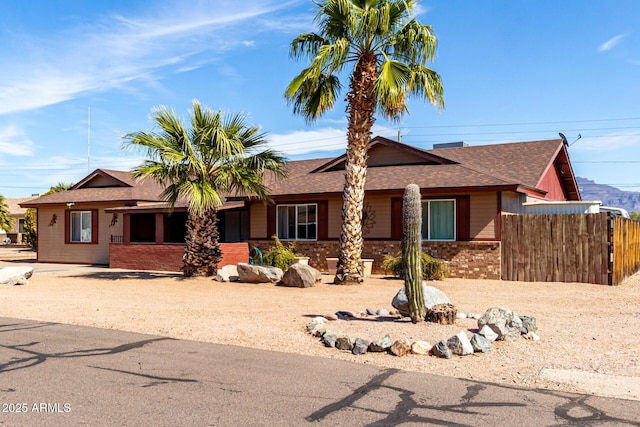 ranch-style house with brick siding, a shingled roof, and fence