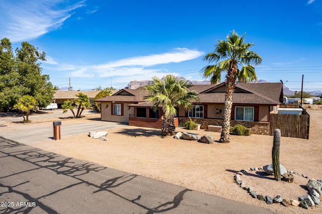 single story home featuring a shingled roof, brick siding, fence, and driveway