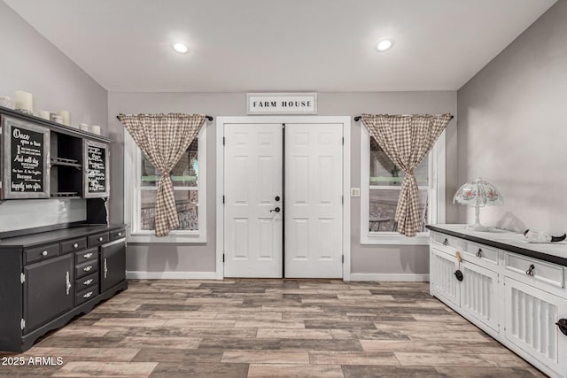 interior space with a healthy amount of sunlight, recessed lighting, wood finished floors, and baseboards