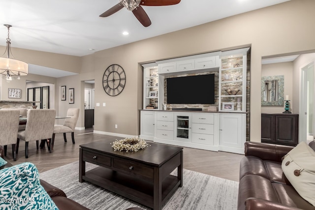 living area featuring ceiling fan with notable chandelier, light wood finished floors, recessed lighting, and baseboards