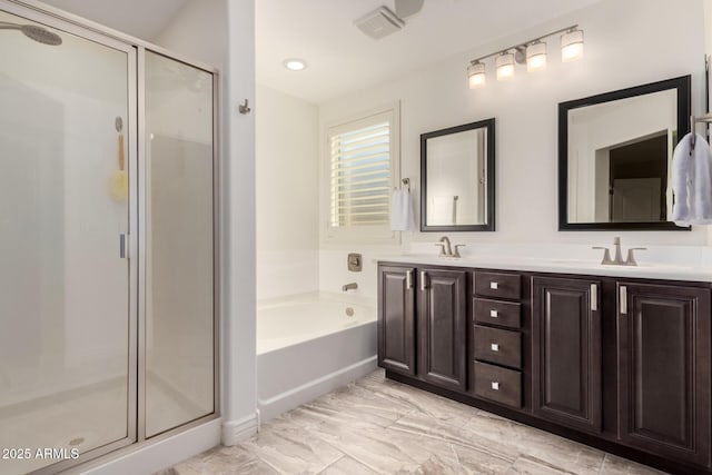 bathroom with double vanity, a garden tub, a sink, and a stall shower