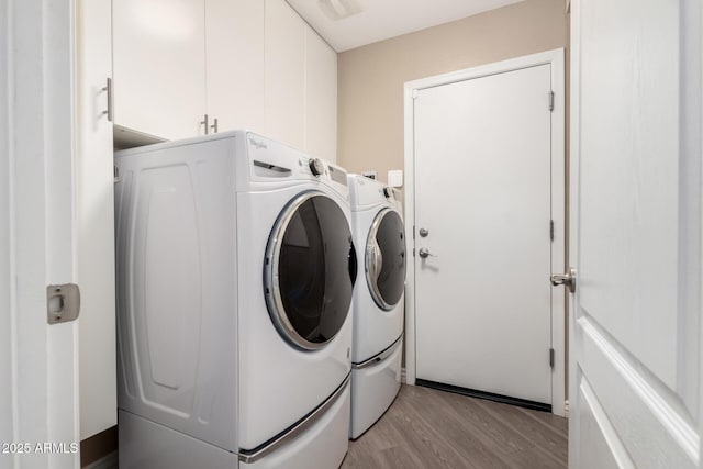 laundry room featuring cabinet space, washing machine and dryer, and light wood-style flooring