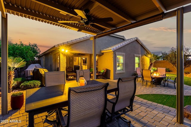 view of patio / terrace with an outdoor fire pit, outdoor dining area, fence, and ceiling fan