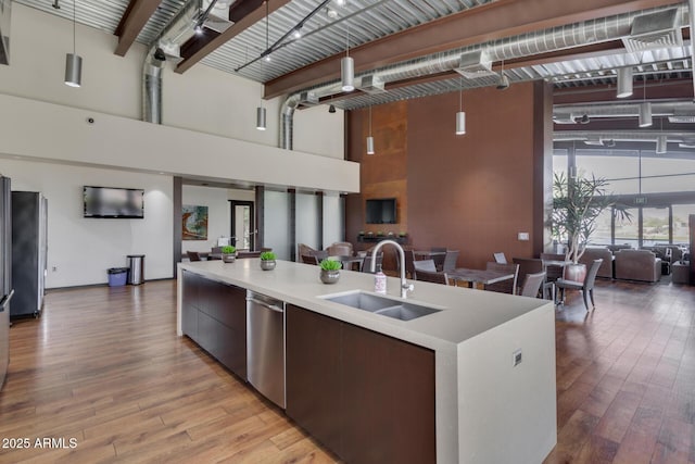 kitchen with open floor plan, a sink, a towering ceiling, and stainless steel dishwasher