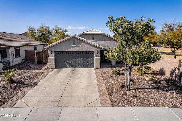 view of front of property featuring driveway, an attached garage, fence, and stucco siding