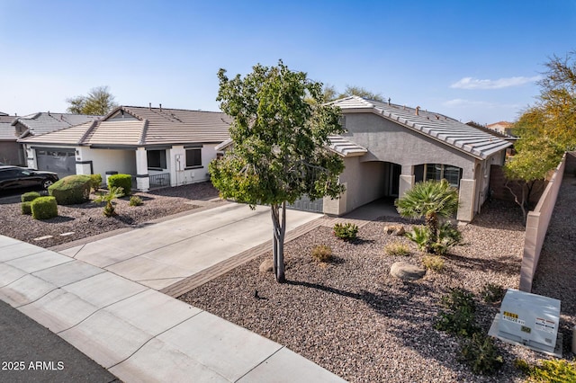 view of front of house with a garage, driveway, a tiled roof, and stucco siding