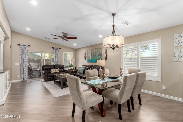 dining space with visible vents, vaulted ceiling, baseboards, and wood finished floors