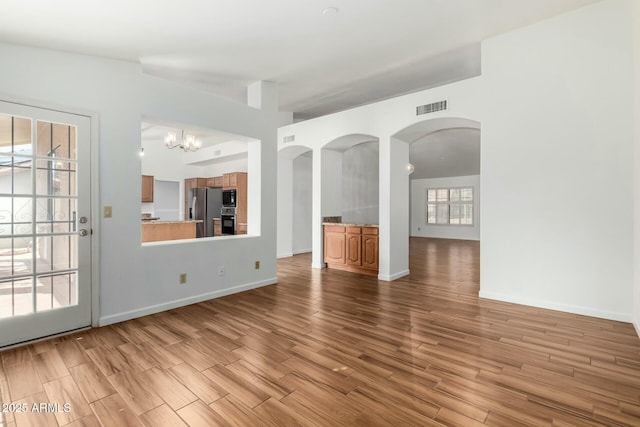 unfurnished living room with light hardwood / wood-style floors and a chandelier