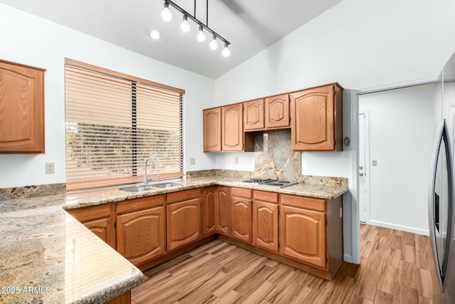 kitchen with sink, light hardwood / wood-style flooring, gas cooktop, light stone countertops, and vaulted ceiling