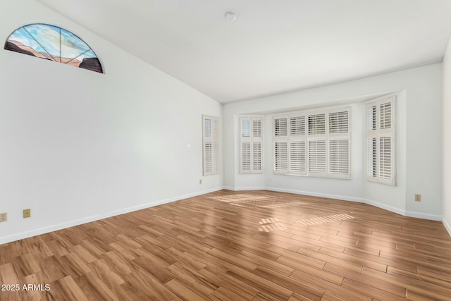 empty room with vaulted ceiling and light hardwood / wood-style floors