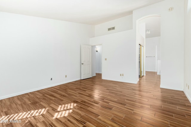 empty room featuring hardwood / wood-style flooring and a high ceiling