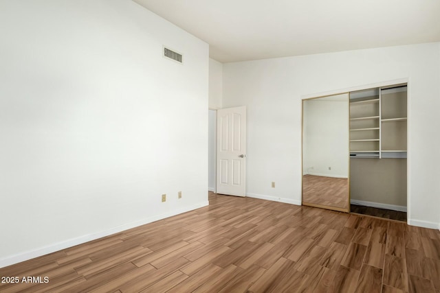 unfurnished bedroom featuring hardwood / wood-style floors, vaulted ceiling, and a closet