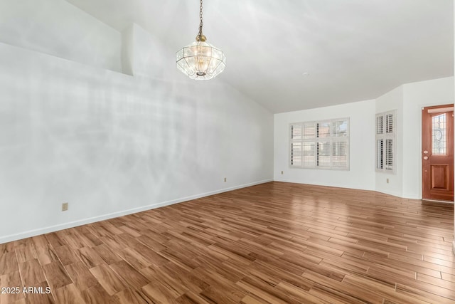 unfurnished living room featuring lofted ceiling, a notable chandelier, and light wood-type flooring