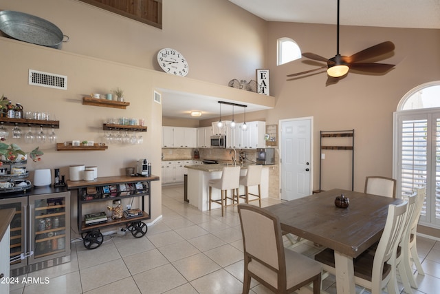 tiled dining area with high vaulted ceiling, beverage cooler, and ceiling fan