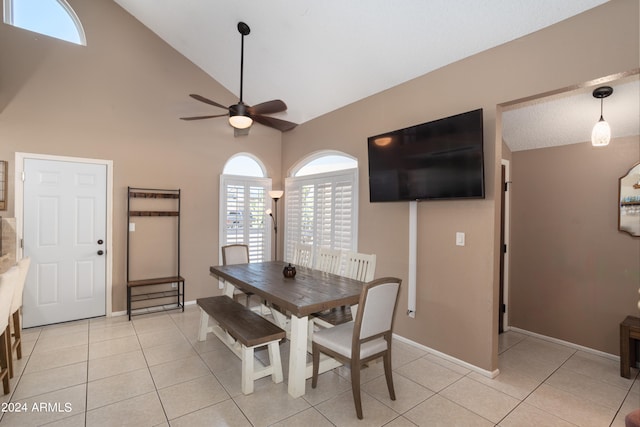 dining space with ceiling fan, high vaulted ceiling, and light tile patterned flooring