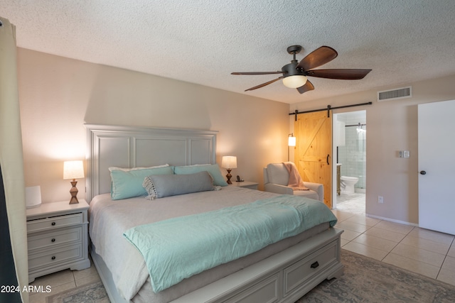 tiled bedroom with ceiling fan, ensuite bath, a textured ceiling, and a barn door