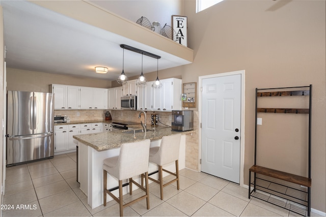 kitchen featuring kitchen peninsula, white cabinets, tasteful backsplash, appliances with stainless steel finishes, and light stone counters