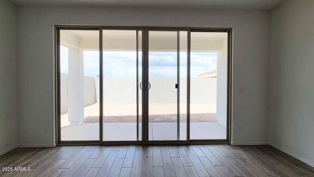 doorway to outside featuring a healthy amount of sunlight, wood finished floors, and baseboards