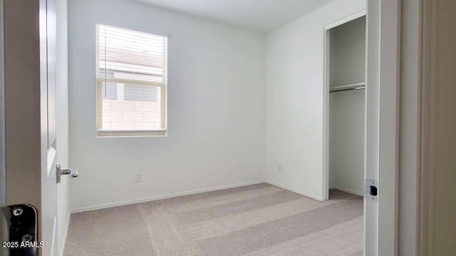 unfurnished bedroom featuring a closet, baseboards, multiple windows, and light carpet