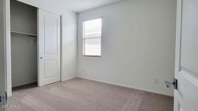 unfurnished bedroom featuring carpet floors, baseboards, and a closet