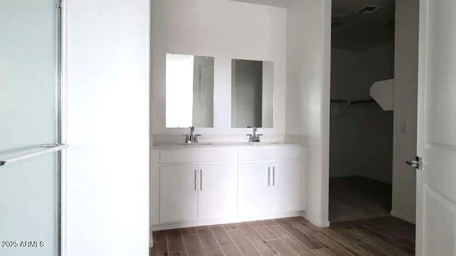 bathroom with a sink, double vanity, and wood finished floors