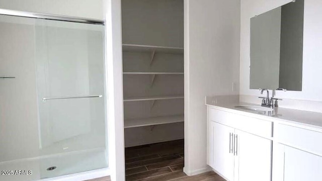 full bath with a spacious closet, a shower stall, wood finish floors, and vanity
