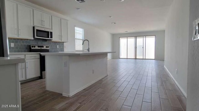 kitchen with open floor plan, appliances with stainless steel finishes, wood finished floors, and baseboards