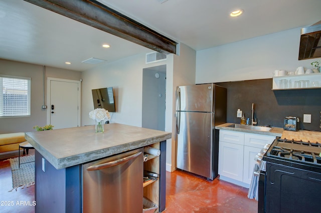 kitchen featuring sink, stainless steel appliances, a center island, and white cabinets