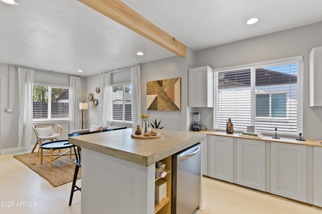 kitchen with a breakfast bar area, dishwasher, white cabinetry, beam ceiling, and a center island